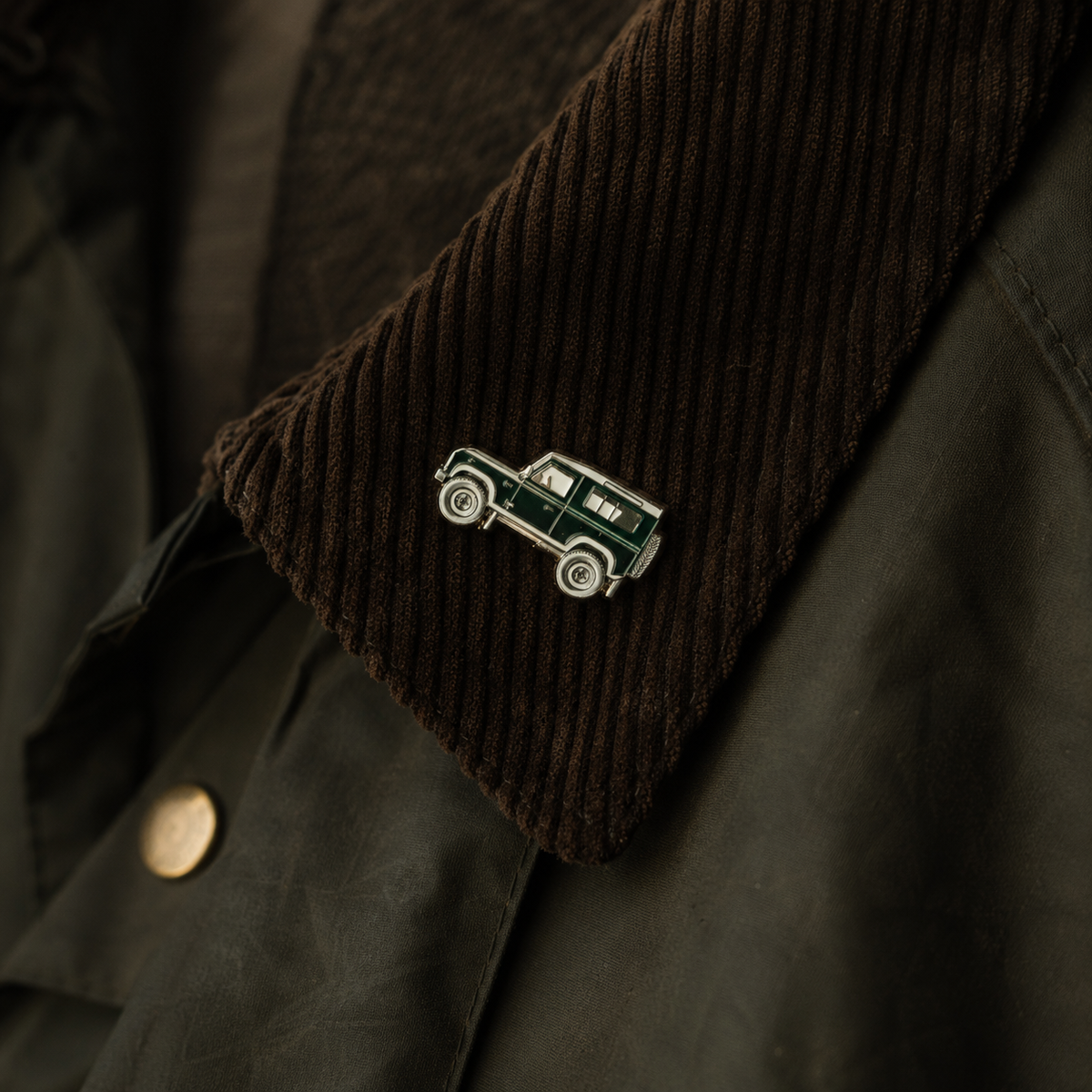 Pin Landy – Geländewagen-Pin am Cordkragen einer grünen Wachsjacke