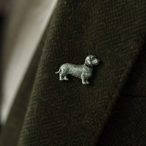 Pin Wilhelm – Rauhaardackel aus Zinn am Revers eines olivgrünen Wollmantels