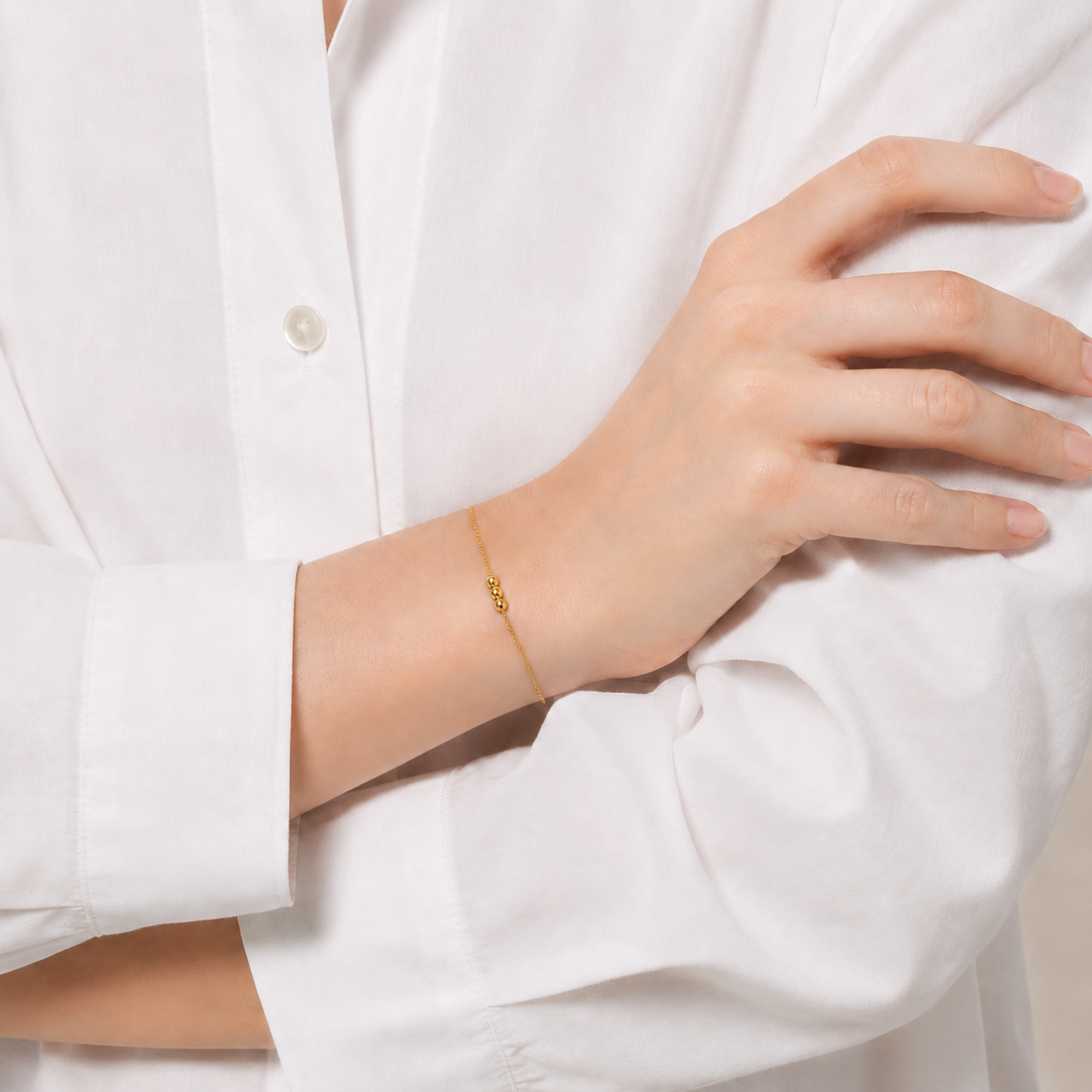 Adelsband Imperial in Gelbgold am Handgelenk einer Frau zur weißen Bluse