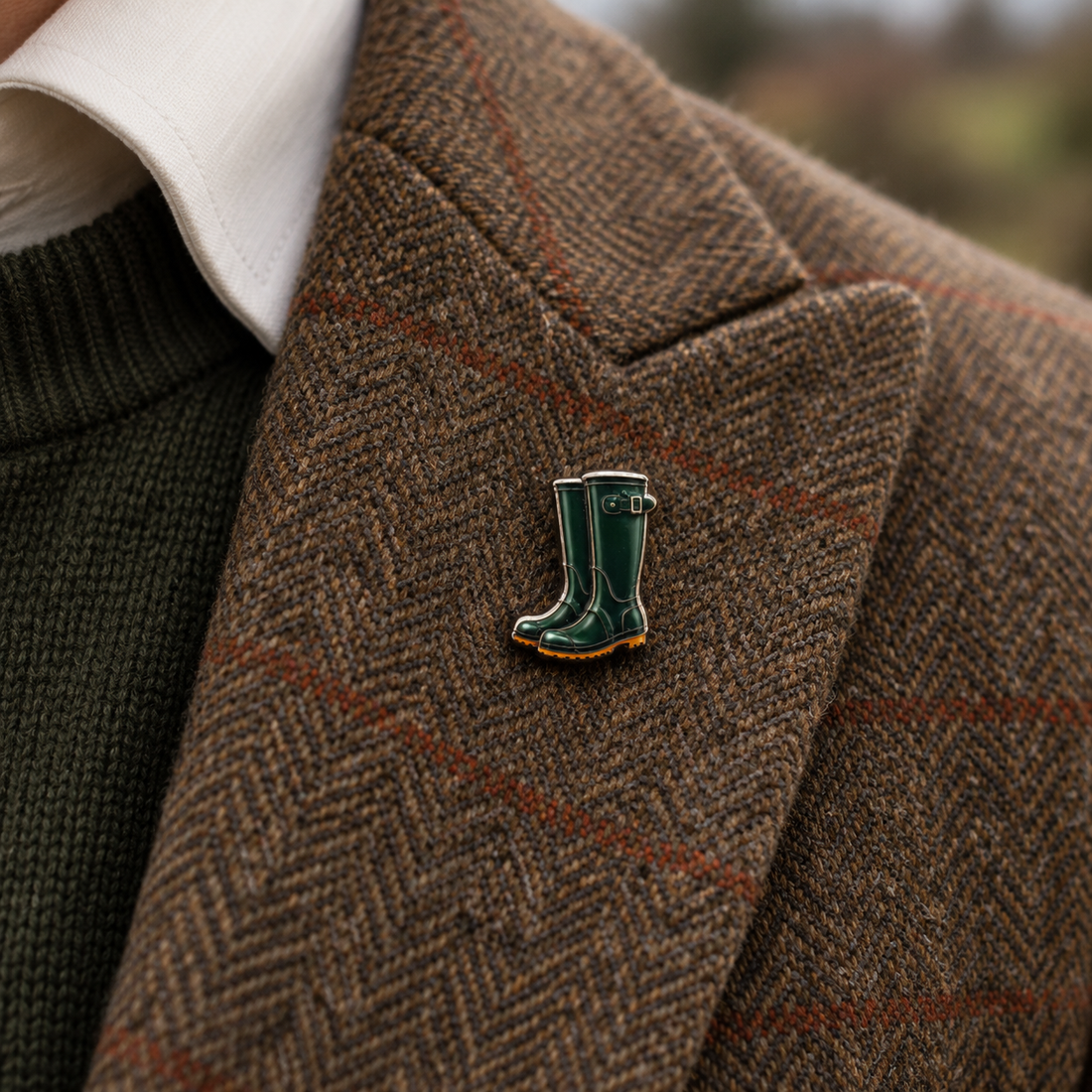 Pin Wellis: Gummistiefel-Pin am Revers eines braunen Tweed-Sakkos